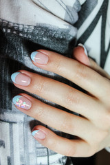 Beautiful creative French manicure gel Polish on natural nails with a design gel Polish drawn by hand on the hands of a fashionable woman