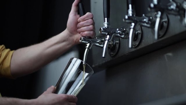 bartender pouring a pint of beer from stainless steel tap