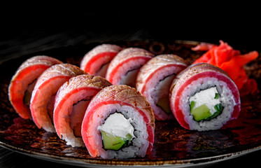  sushi roll with tuna, avocado, cream cheese, cucumber, rice in plate on black wooden table background