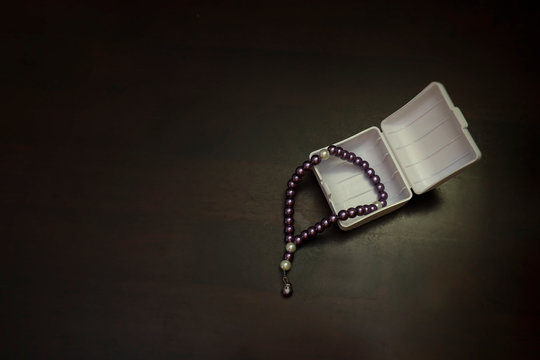 View of light fall on the prayer beads isolated on a dark wooden table.  Faith and religious concept 