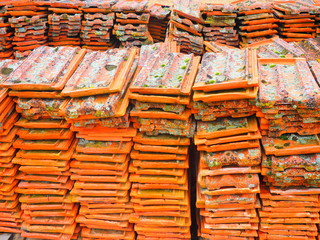 Tejas de barro con musgo y liquen amontonadas en el campo.