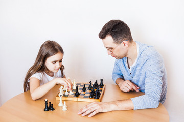 Girl and dad play a game at home, chess, puzzle for brain development, mental intelligence, child development, school, home, quarantine, vacation, time with family
