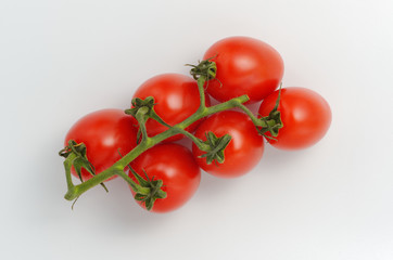 Red cocktail tomatoes on a branch. Light gray background. View from above. Soft shadows.
