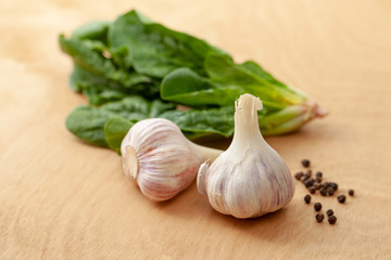 Garlic, spinach leaves and peper on a wooden background