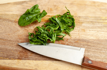 Cooking spinach leaves on a cutting Board in the kitchen.