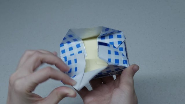 The girl opens a pack of butter