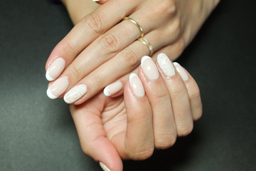 Fashionable gentle manicure gel Polish on natural nails with a white monogram pattern on the hands...