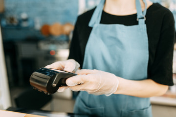  Precautions during quarantine. A gloved waiter with a cashless payment terminal.