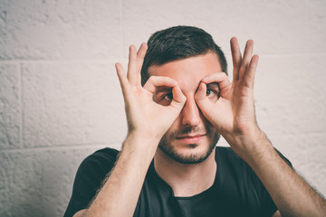 man looking through hands, making binoculars