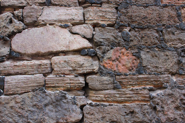 Old wall made of rocks. Medieval rocky surface. Texture of an old rocks sticked up with a cement.