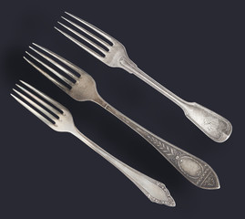 Vintage old worn-out forks isolated on a black background. Retro silverware.