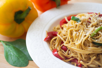 Chinese egg noodles in soy sauce with colorful bell peppers, greens and spring onions with sesame seeds sprinkled on top