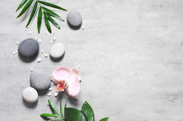 Spa concept on stone background, palm leaves, flower, zen, grey stones, top view, copy space.