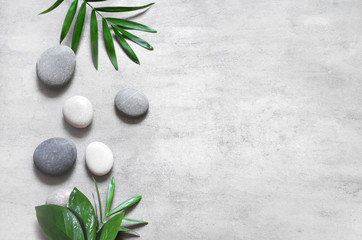 Obraz na płótnie Canvas Grey spa background, spa concept, palm leaves and grey stones.