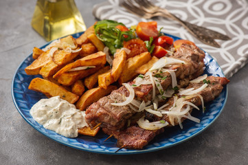 Souvlaki served with fried potatoes, tzatziki dip and pita bread, greek cuisine.