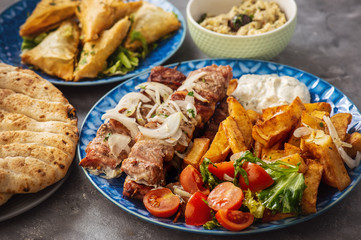 Souvlaki served with fried potatoes, tzatziki dip and pita bread, greek cuisine.