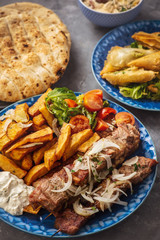 Souvlaki served with fried potatoes, tzatziki dip and pita bread, greek cuisine. - obrazy, fototapety, plakaty