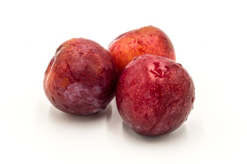 Three ripe red round plums isolated
