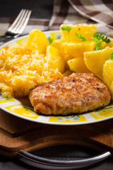 Minced pork cutlet served with potatoes and sauerkraut salad.