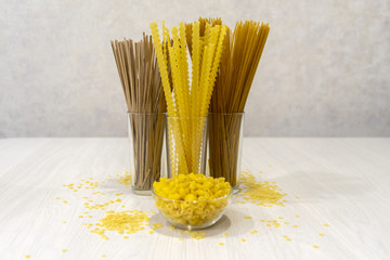 Pasta made of durum wheat, buckwheat, bran, in glass dishes, on a light background