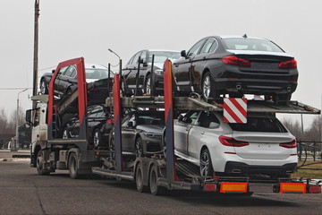Two-level car carrier truck transports european new cars, rear side view, delivery autos logistics, automobile transportation