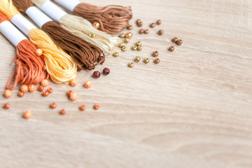 Materials for bracelets - beads and yarn on wooden table. Colorful photography with copy space for text. Selected focus.