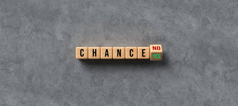 cubes with letters showing the word CHANCE and the answer YES or NO on concrete background