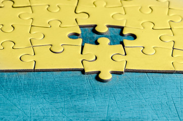 the unexpected solution. yellow jigsaw/puzzle with one piece at wrong position, on a blue table...