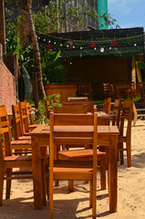 Plakat Wooden tables and chairs on the beach. Outdoor cafe. No people