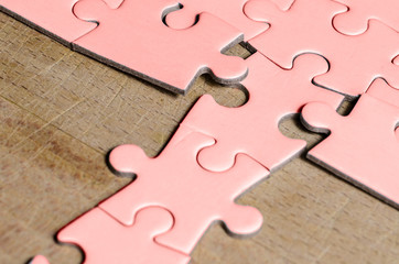 the unexpected solution. pink jigsaw/puzzle with a row in wrong position, over  wooden table background, symbol of problem solving and new vision