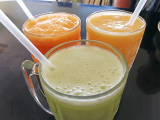 close-up of three glasses of freshly squeezed juice with tubes. Delicious, nutritious and healthy drinks