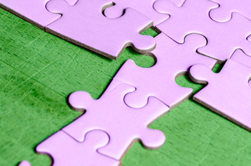 the unexpected solution. purple jigsaw (puzzle ) with a row in wrong position, on a green table...