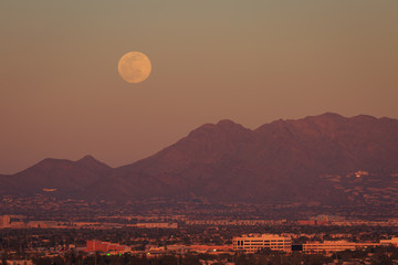  waiting for and then seeing a full moon rise from behind a colorful desert mountain with its thin...
