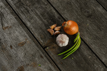 Garlic heads and garlic cloves with green onion on the wooden background