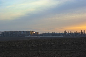 Obraz premium The beginning of urban development behind a plowed field in spring