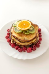 Top view of pancakes with orange, kiwi and raspberries.
