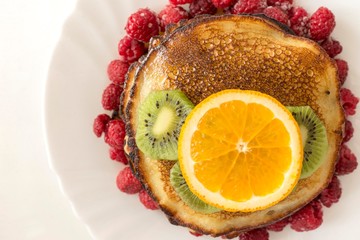 Top view of pancakes with orange, kiwi and raspberries.