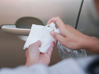 Close up of hand spraying a sanitizer from a bottle for disinfecting door handle of a car. Antiseptic,disinfection ,cleanliness and healthcare,Anti bacterial and Corona virus, COVID-19.