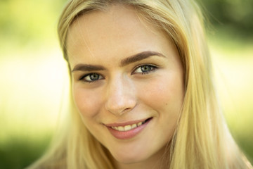 Naklejka premium Close-up of Female Face, smiling blond Girl In Nature