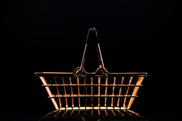 golden metal basket for a grocery store on a dark background with reflection