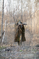 Tall man dressed in a tactical military suite with a machine gun and a gas mask in the reeds in the autumn or spring