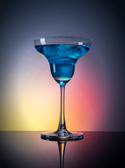 
Glass with blue drink and ice on a color gradient background