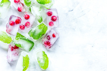 Fototapeta na wymiar mint and red berries in ice cubes stone background top view mockup