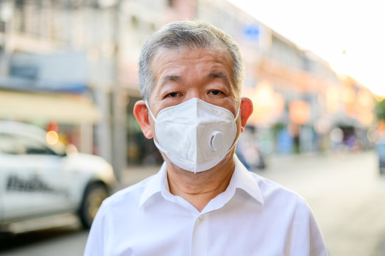 Portrait of a senior man wearing protective N95 mask on street city
