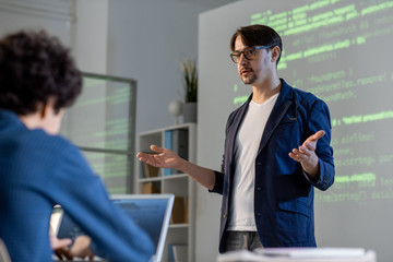 Young teacher or coach in casualwear and eyeglasses explaining main points