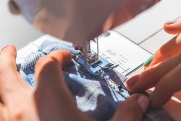 Sewing at home: Woman is sewing at home, close up of sewing needle, textile and hands