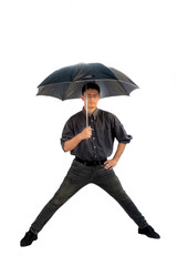 Full-length shot of a man wearing a grey colored shirt and black jeans with a black umbrella and posing with widen legs over white background.