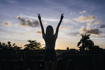 Shapely cute female model posing with hands up while looking at evening sky. Outdoor portrait of...
