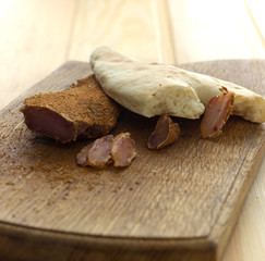 A plate of meat delicacies for beer. Handicraft production of meat snacks. Armenian meat basturma. Beef jerky and spices on an old wooden table