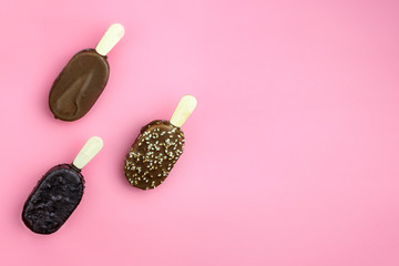 Ice cream sticks with chocolate, roasted almonds and sesame on pink background. Top view. Copy space. Pattern